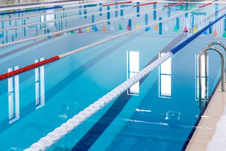 Swimming pool with marked red and white lanes. Empty swimming pool without people with quiet standing water. Water sports in indoor pool.