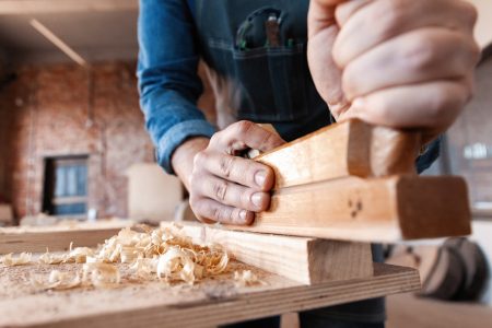 carpenter working with plane on wooden background